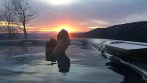 Un lago ghiacciato con un tramonto sullo sfondo e un molo di legno che si protende nell'acqua.