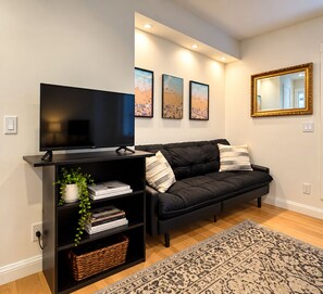 A modern living room with a black sofa, a flat-screen TV, and decorative wall art.