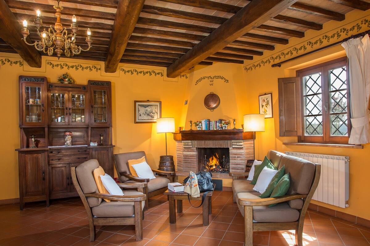 Uma sala de estar aconchegante com móveis de madeira, lareira e um lustre.