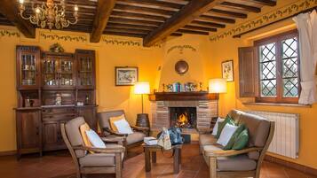 A cozy living room with wooden furniture, a fireplace, and a chandelier.