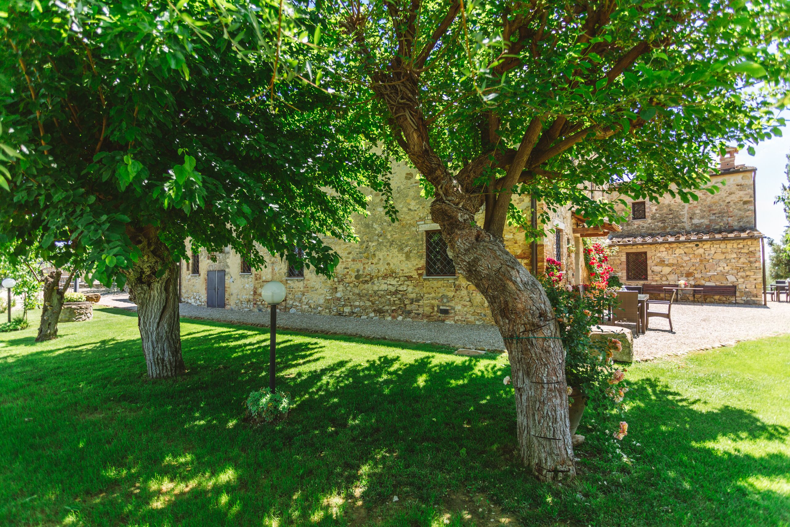 Ein Steinhaus mit rustikalem Aussehen, einem gepflegten Rasen und einem großen Baum, der Schatten spendet.