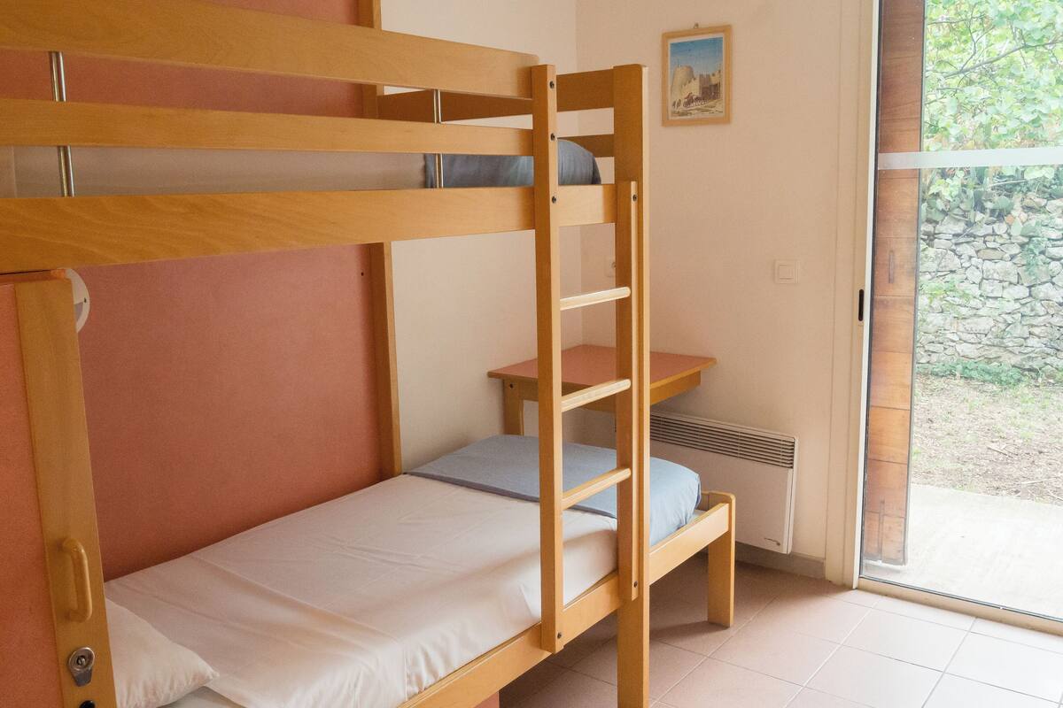 Un lit superposé avec un lit inférieur et une petite table accompagnée d’une chaise.