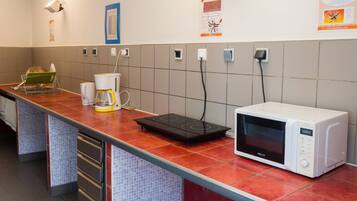 A kitchen with a microwave, coffee maker, and a toaster. There are tiled walls and a red countertop.