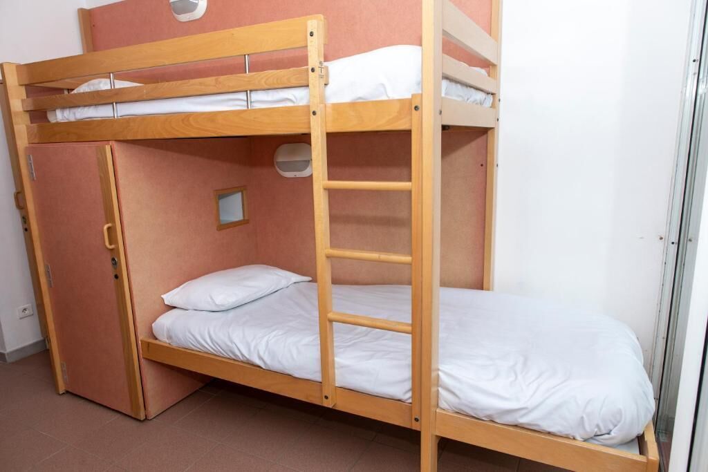 A bunk bed with a ladder, a small window, and a door.