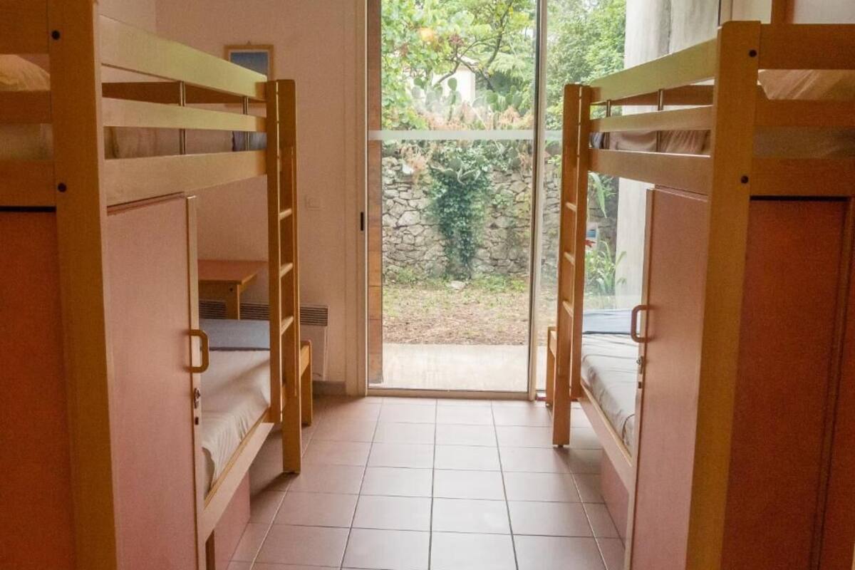 Une chambre avec des lits superposés, une fenêtre et une vue sur la verdure.