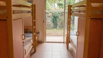 Una habitación con literas, una ventana y vistas al verdor exterior.