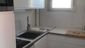 A compact kitchen with white cabinetry, a black sink, and a window above the countertop. - LES BALCONS ROUGES Face Mer - Impressive sea view (SAINTE CECILE)