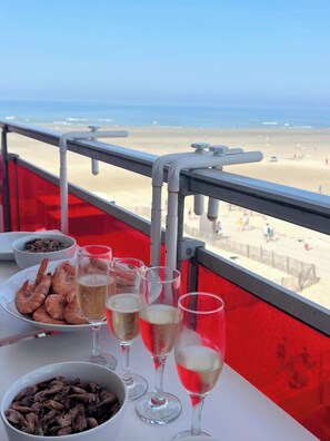 A table with seafood and champagne glasses, overlooking a beach.