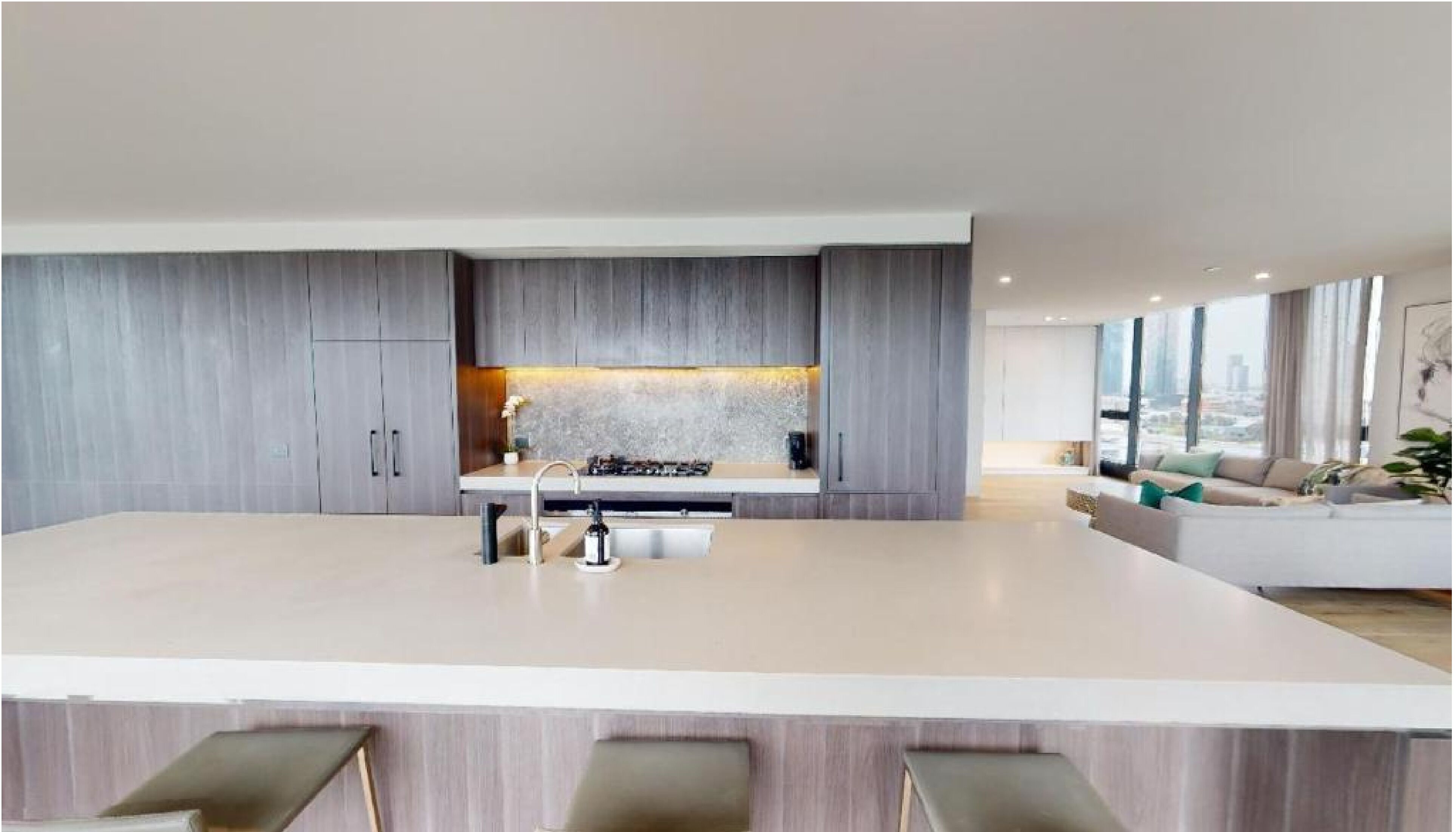 Una cocina moderna con una isla central, armarios grises y un amplio ventanal con vistas a la ciudad.