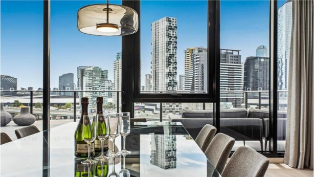 Een moderne vergaderruimte met uitzicht op de skyline van de stad, grote ramen en een tafel gedekt met wijnglazen en flessen.