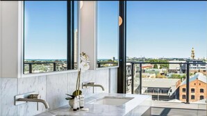 A modern bathroom with a large window, a marble sink, and a vase with white flowers. - Luxury Penthouse with Bay and City Views (South Melbourne)
