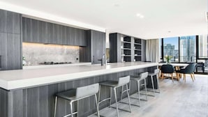Een moderne keuken met een groot schiereiland, barstoelen en een eethoek met uitzicht op de stad.