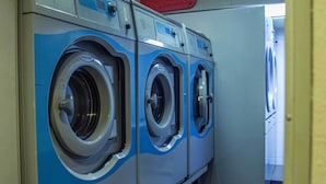 A row of front-loading washing machines in a commercial laundry room.