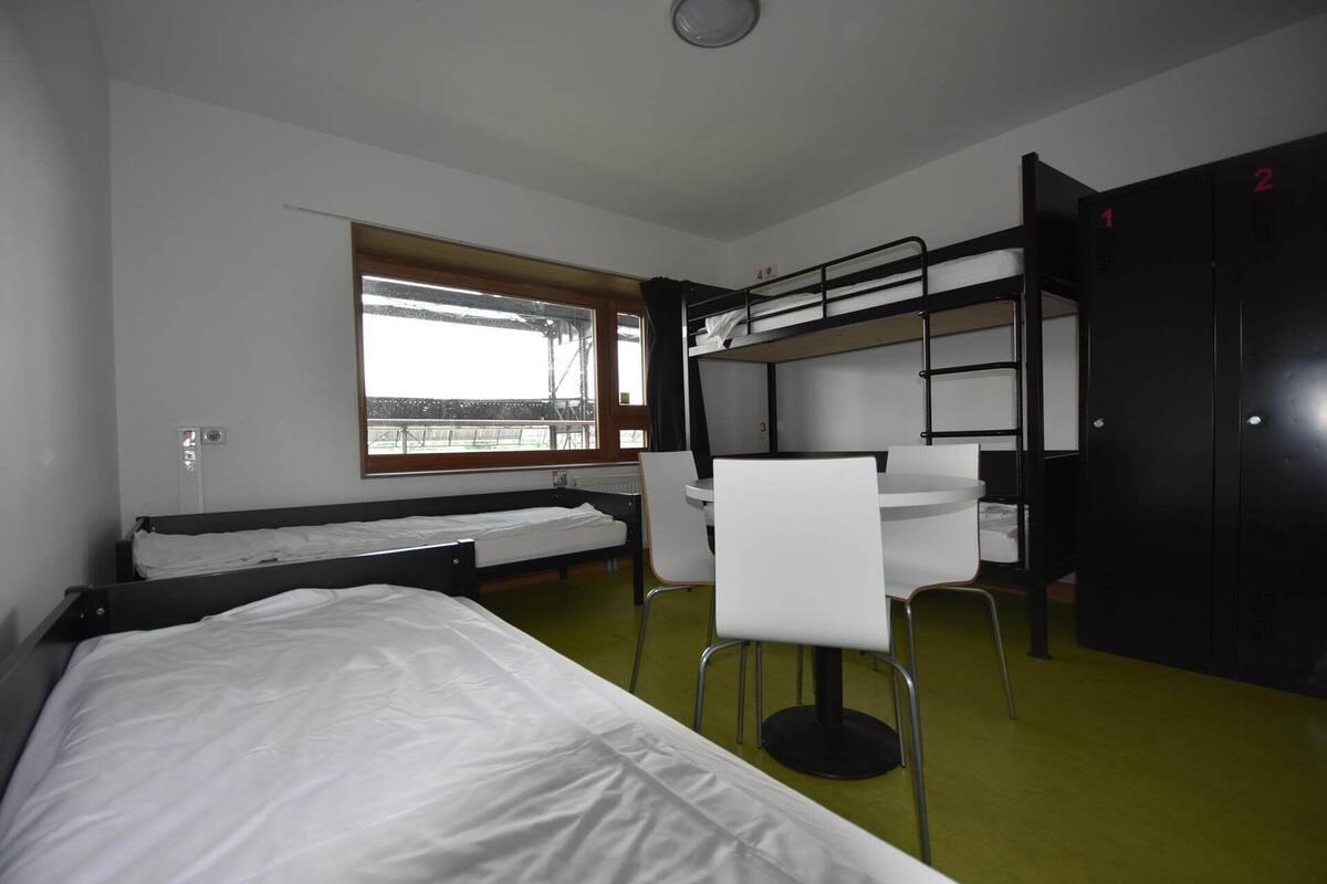 Una habitación tipo dormitorio con literas, un escritorio y una silla.