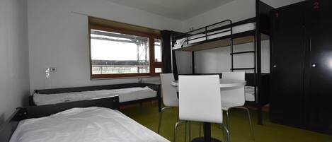 Una habitación tipo dormitorio con literas, un escritorio y una silla.