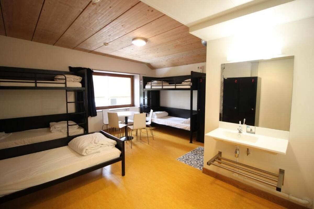 Un dormitorio con literas, un escritorio, sillas, un lavabo y un espejo.