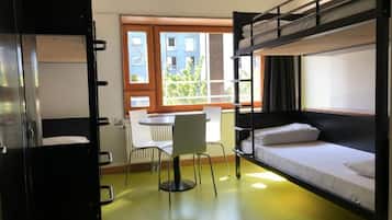 A dormitory room with bunk beds, a desk, and a chair.
