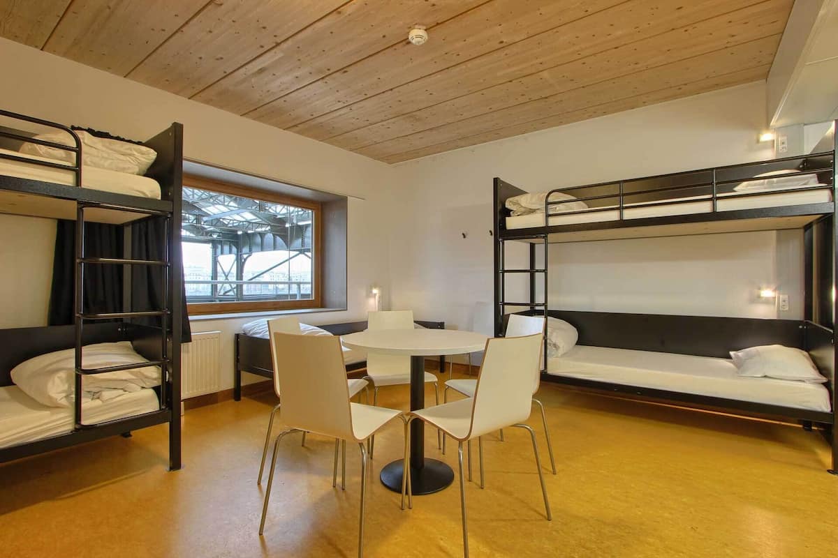 Un dormitorio con literas, una mesa redonda y cuatro sillas.