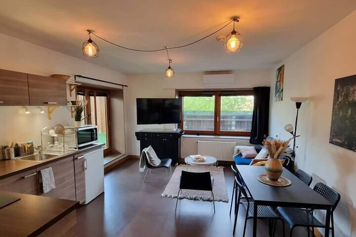 Una cocina moderna con armarios de madera, horno empotrado y comedor con mesa y sillas.