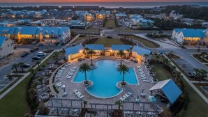 Un resort con piscina central, varias edificaciones y vistas al atardecer.