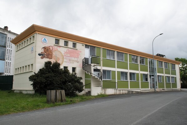 Un edificio de fachada verde y beige, con una escalera y un mural de un perro.