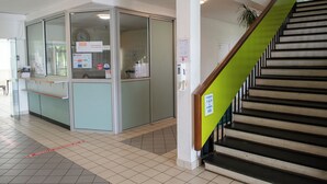 Zona de recepción con mostrador, escalera y un cartel con los números de las habitaciones.