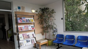 Un área de recepción con un banco de madera, una planta en maceta y un tablón de anuncios con revistas.