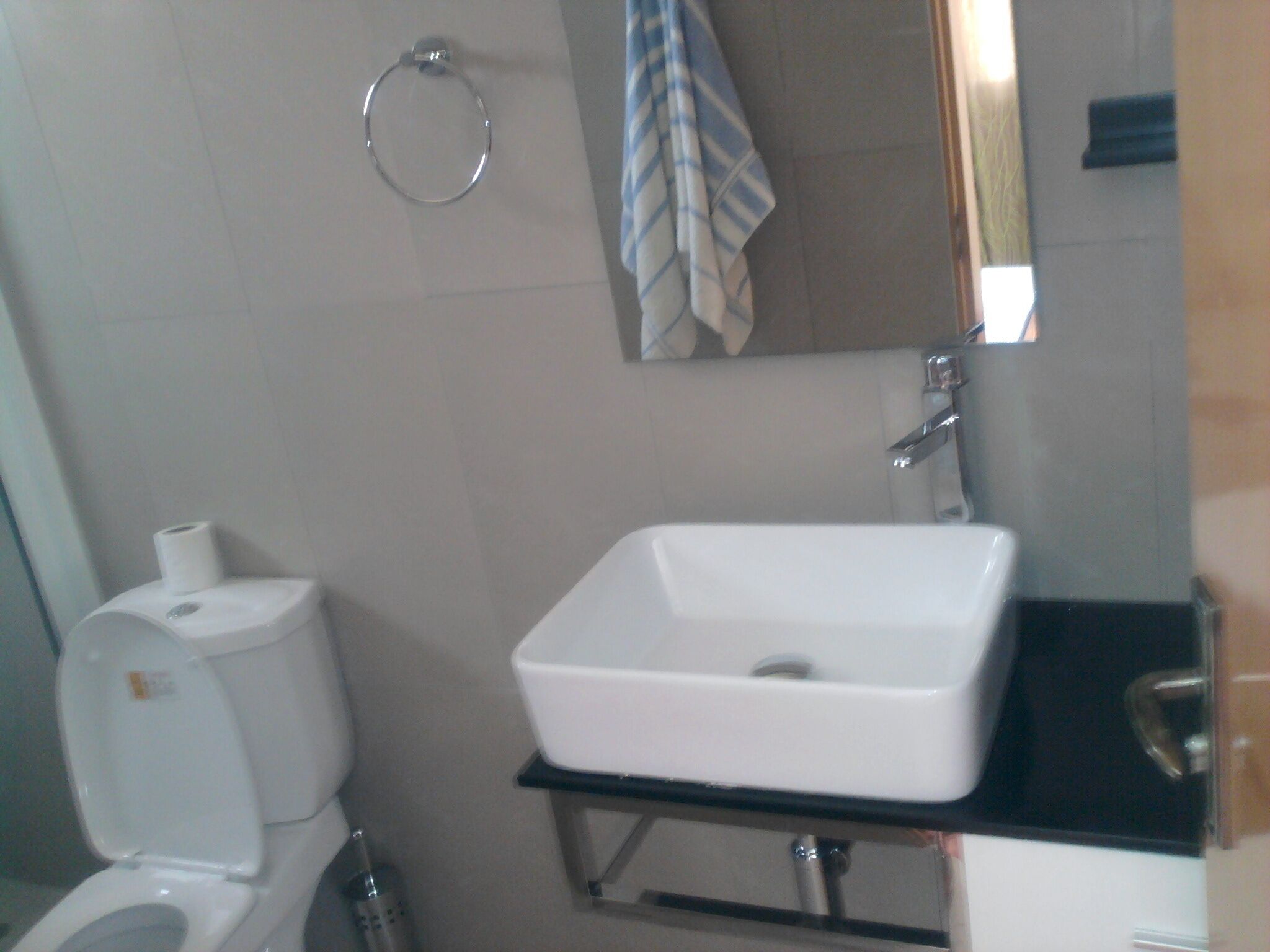 Un bagno con il water bianco, un lavandino bianco e un asciugamano su un porta-asciugamani.
