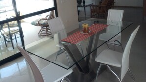 Un espace repas moderne avec une table en verre, des chaises blanches et un centre de table composé de bougies.