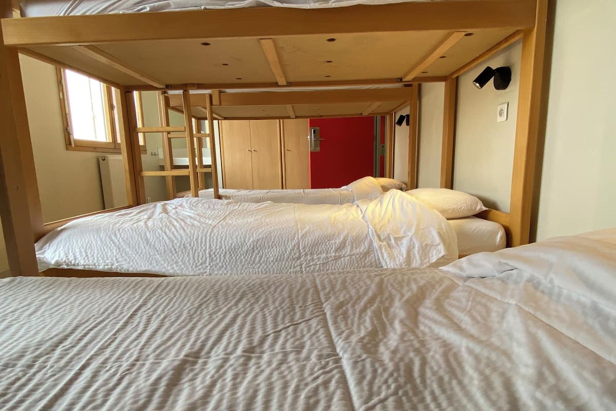 Une chambre avec un lit superposé, des têtes de lit en bois, une échelle et un mur rouge.