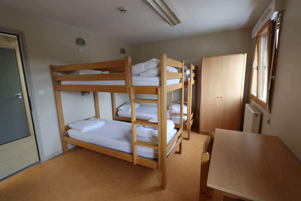 Une chambre avec un lit superposé, un bureau et une armoire en bois.