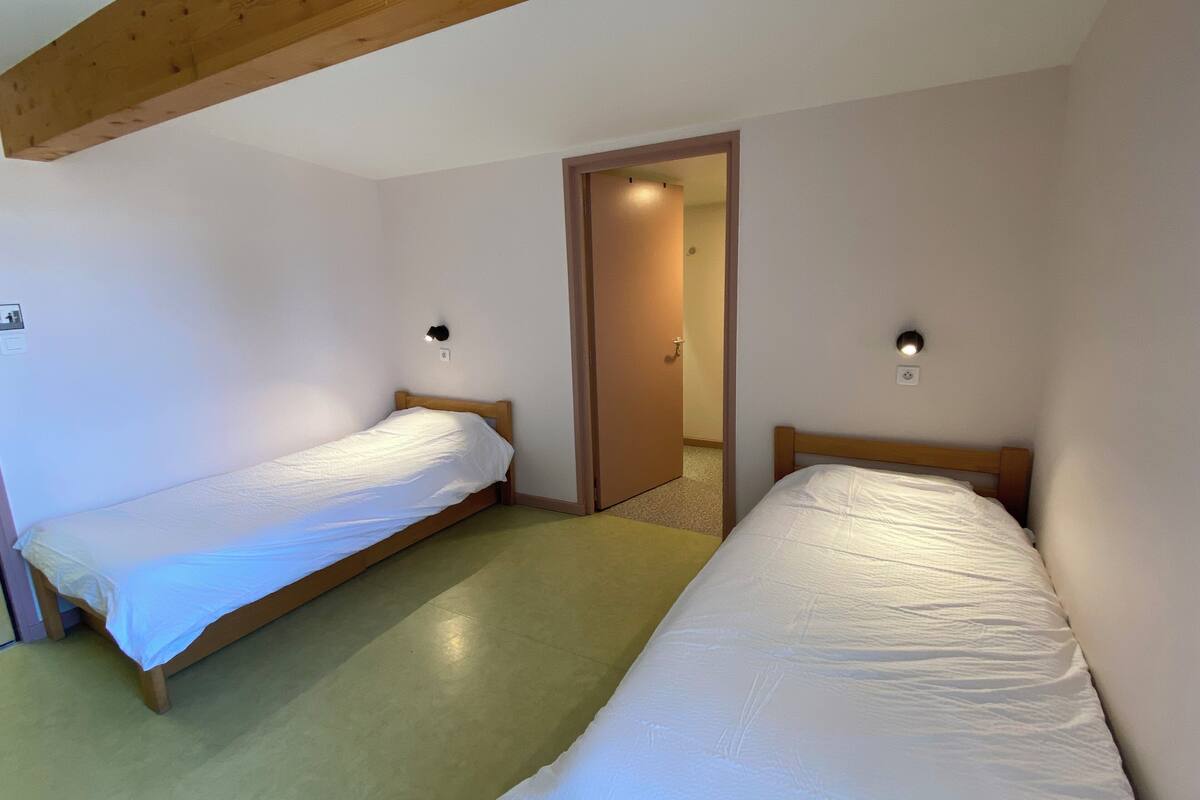 Une chambre avec deux lits simples, des têtes de lit en bois et un plafond en pente.