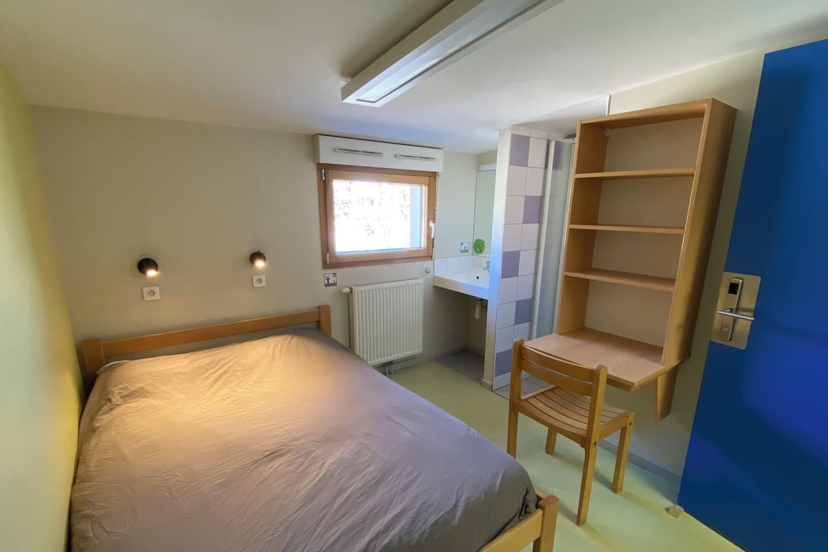 Une chambre à coucher de taille réduite, comprenant un lit, un bureau et une chaise.
