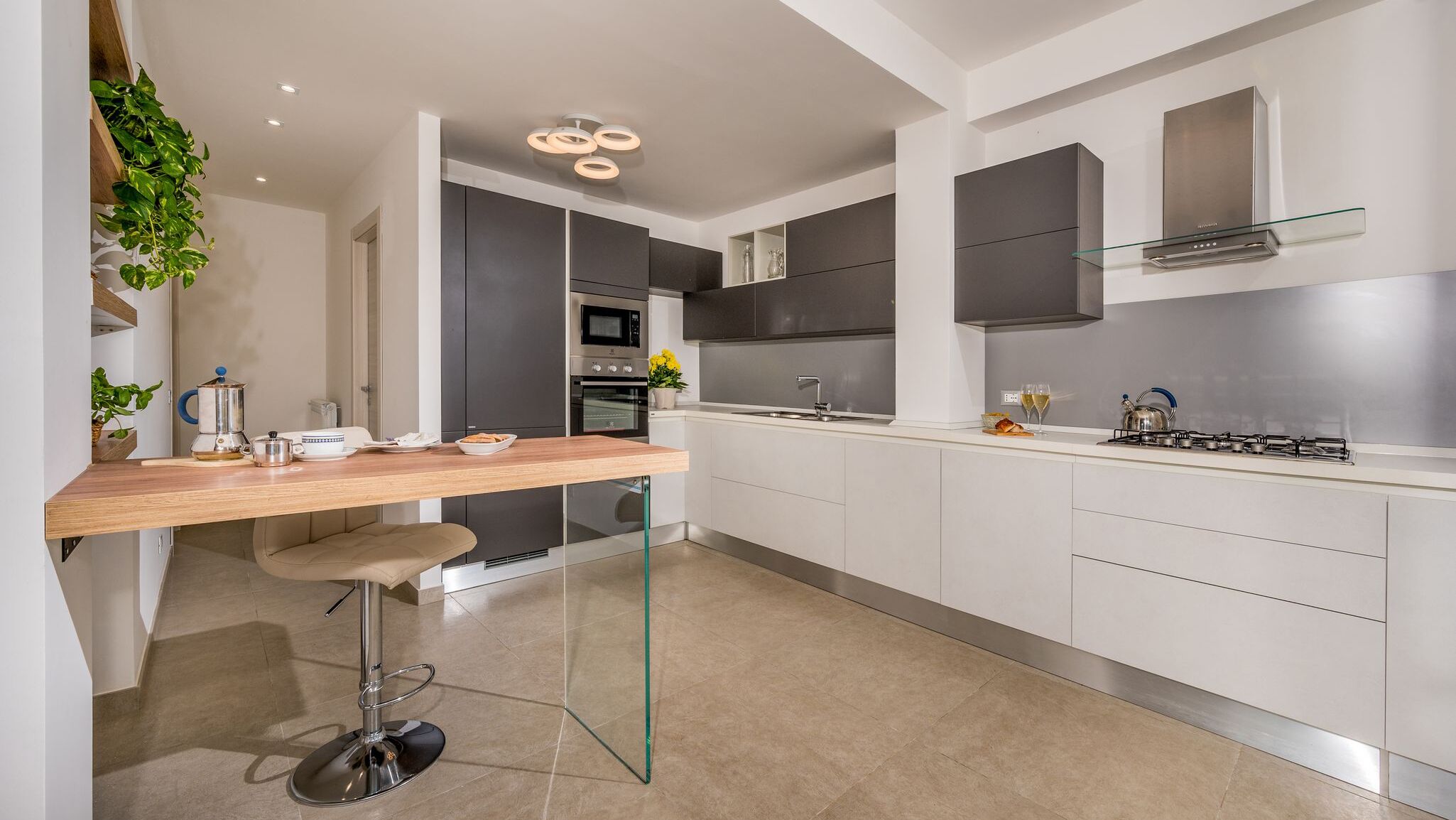 A modern kitchen with a wooden bar counter, stainless steel appliances, and a glass backsplash.