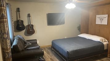 Une chambre à coucher avec un lit, un téléviseur fixé au mur et deux guitares.
