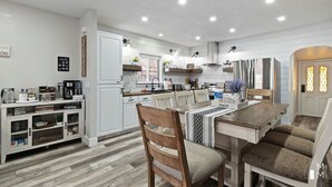Una cocina moderna con armarios blancos, una mesa de comedor de madera y un banco empotrado.