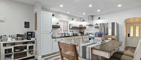 A modern kitchen with white cabinetry, a wooden dining table, and a built-in bench.
