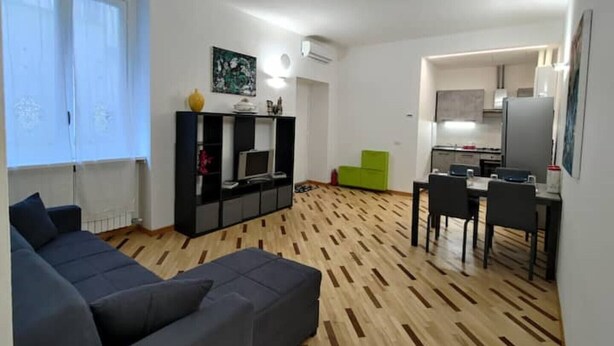 Un salon moderne avec un canapé, un téléviseur et un coin repas comprenant des chaises et une table.
