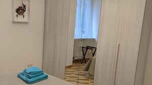 Une chambre à coucher avec un lit, un miroir, une fenêtre et une petite table avec une chaise.