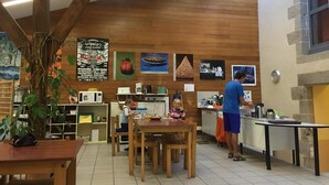 A restaurant interior with wooden walls, a high ceiling, and a dining area with tables and chairs. - Auberge de Jeunesse HI Pontivy (Pontivy)