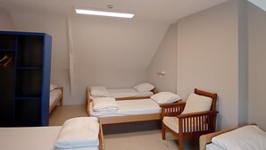 A dormitory room with three bunk beds, a wooden chair, and a blue wardrobe. - Auberge de Jeunesse HI Pontivy (Pontivy)