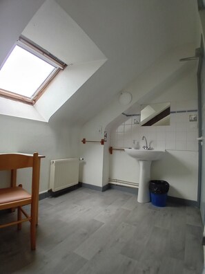 A small, bright room with a skylight, a wooden chair, a white sink, and a radiator. - Auberge de Jeunesse HI Pontivy (Pontivy)