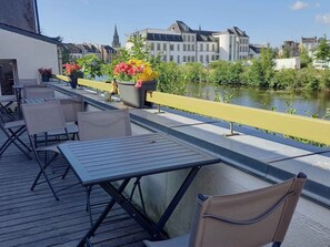 A terrace with outdoor seating, a river view, and buildings in the background. - Auberge de Jeunesse HI Pontivy (Pontivy)