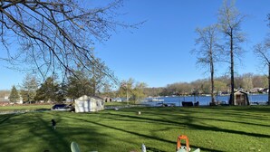 A grassy park area with a small shed, a few chairs, and a toy vehicle. - Charming Lakefront Cottage (Vandalia)