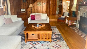 A cozy living room with a wooden interior, a sofa, a coffee table, and a fireplace. - Charming Lakefront Cottage (Vandalia)
