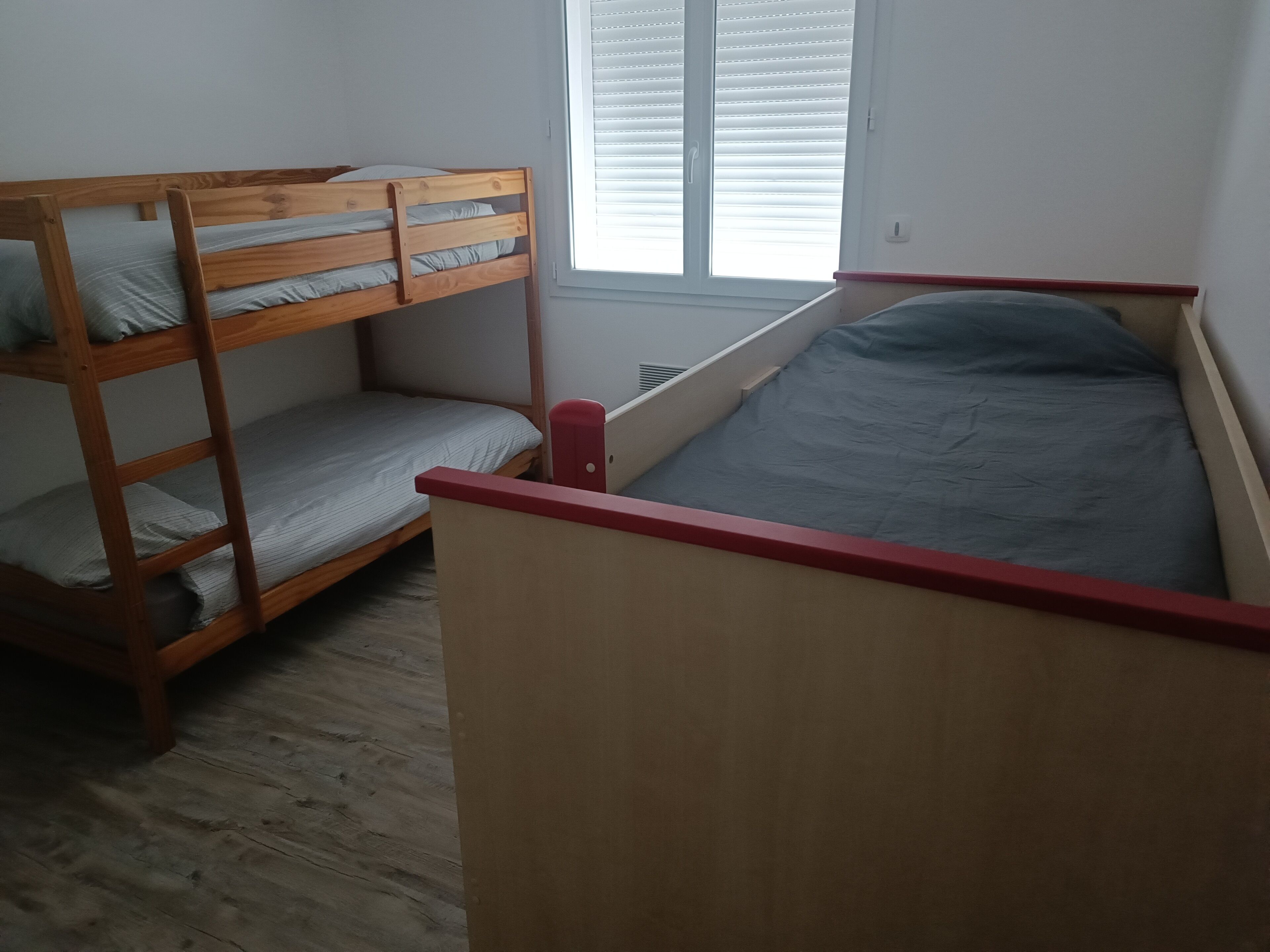 A bunk bed with a red frame and a single bed with a red headboard.