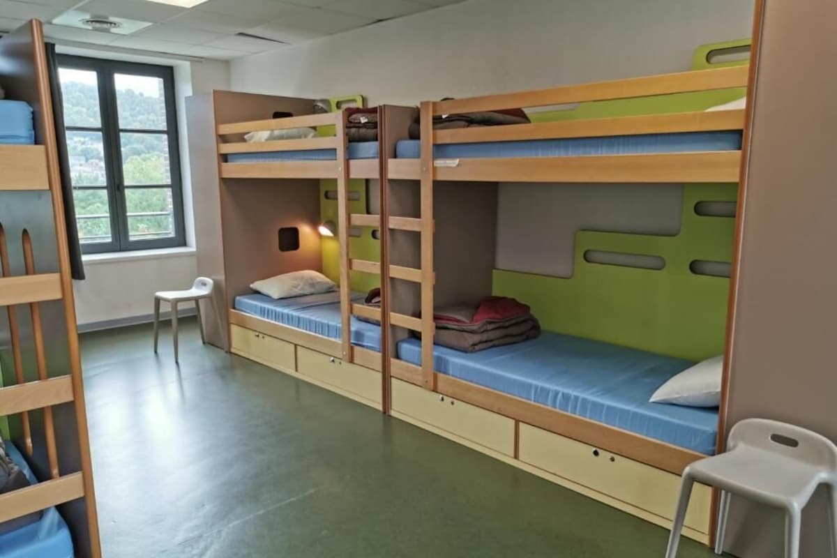 A bunk bed room with a window, a desk, and a chair.