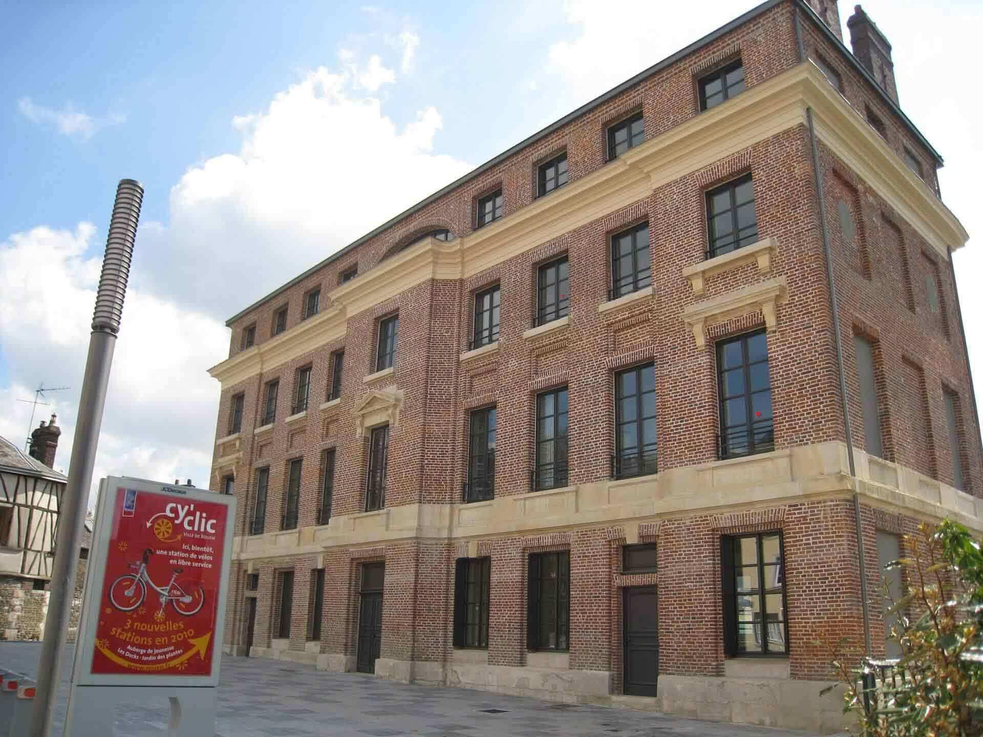 A large brick building with multiple windows and a sign advertising a bicycle service.