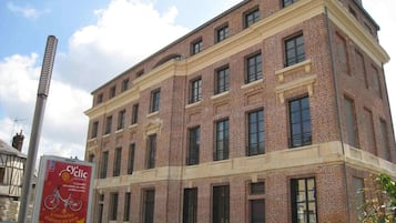 A large brick building with multiple windows and a sign advertising a bicycle service.