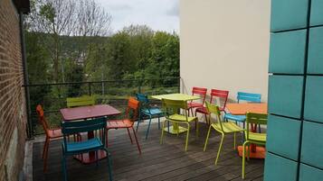 Eine Holzterrasse mit bunten Gartenmöbeln, darunter ein Tisch und Stühle, mit Blick auf einen Garten.